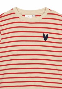 Suéter crema con rayas rojas horizontales, cuello redondo y un logo de corazón marino en el pecho. Textura de tejido suave.