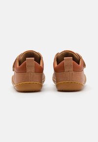 Helle Lederschuhe mit glatter Textur, ausgestattet mit einem weichen Obermaterial, rundem Schnitt und einem Klettverschluss für sicheren Halt. Dicke Gummisohlen.