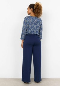 Navy blue long pants with a wide leg cut, paired with a patterned navy blouse featuring a paisley design and three-quarter sleeves.