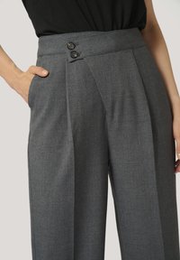 Gray tailored trousers with a smooth texture, wide legs, and two black buttons on the waist. Features side pockets and sharp pleats.