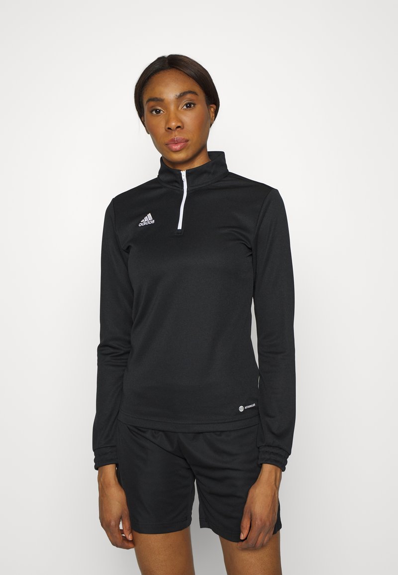 Crni atletski dugi rukav s patentnim zatvaračem, izrađen od tkanine koja upija vlagu, s malim bijelim Adidas logotipom na lijevoj strani prsnog koša.