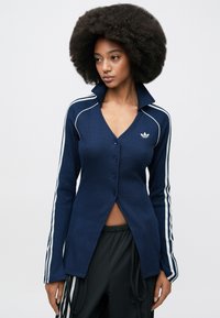 Navy ribbed long-sleeve cardigan with a V-neck, button front, and white stripes along the sleeves. Features an embroidered logo on the chest.