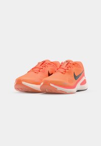 Orange Sportschuhe mit Netzobermaterial, schwarzen Akzenten und verstellbaren Schnürsenkeln. Die strukturierte Sohle verfügt über Dämpfungselemente und Grip.
