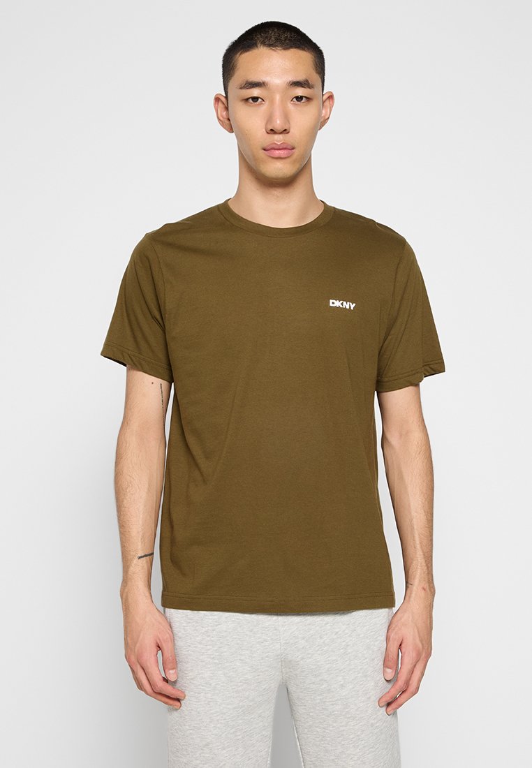 Camiseta de manga corta verde oliva hecha de algodón, con cuello redondo y pequeño logotipo blanco de DKNY en el pecho. Textura suave.