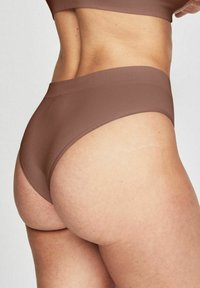 Mutande alte a vita in tessuto marrone a coste, con design senza cuciture e texture liscia, che mostrano una vista dal retro con dettagli di cucitura ridotti al minimo.