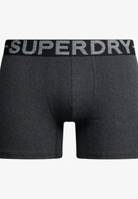 Grijze katoenen boxershorts met een zwarte tailleband, voorzien van een zilveren "SUPERDRY" logo en een aansluitend ontwerp, gladde textuur en gestikte naden.