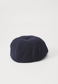 Navy blue fabric beret-style hat with a smooth texture, round shape, and a central tuft. No visible patterns or hardware details.