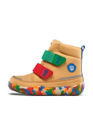 Tan children's boot with green and red Velcro straps, blue logo badge, and multicolored rubber sole.