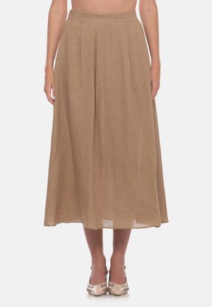 Donna che indossa una gonna marrone chiaro a vita alta, linea a A, lunga fino al ginocchio con pieghe e tacchi beige a punta con dettagli neri.