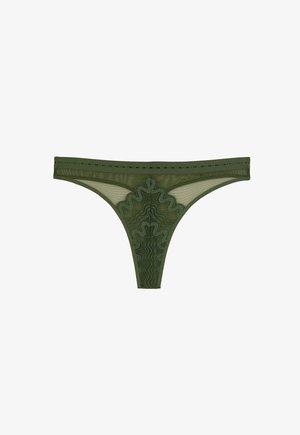 Culotte tanga en maille vert olive avec un motif complexe de dentelle ondulée sur le panneau avant et une ceinture fine avec de petits détails en découpe.