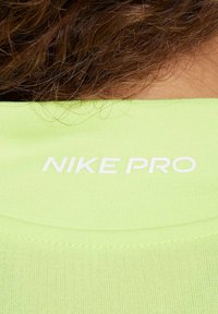 Neon groene sportshirt met een gladde textuur, met het "NIKE PRO" logo in het wit op de achterkant van de halslijn. Eenvoudig ontwerp, slim fit stijl.