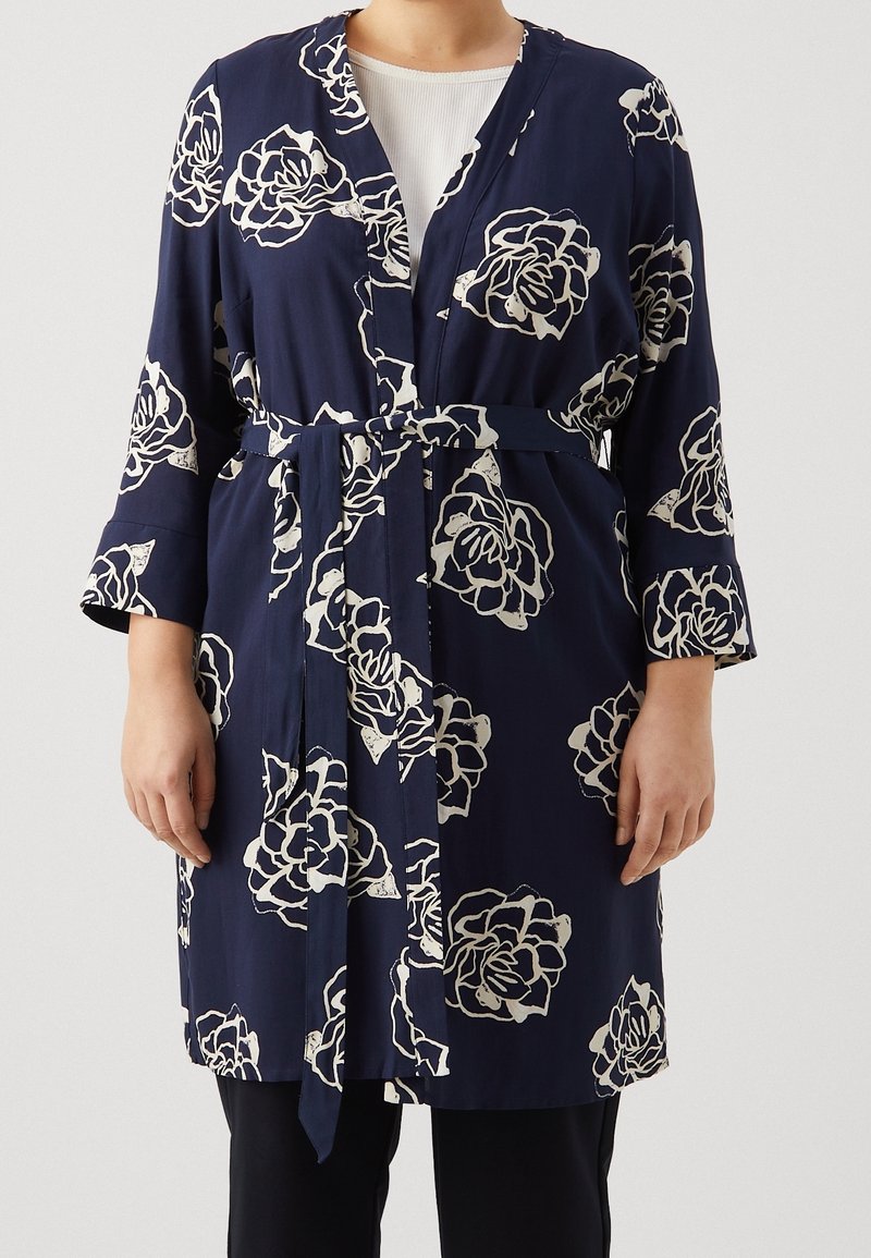 Marineblaue Kimono-Robe mit floralen Mustern, die weiße Rosen zeigen, langen Ärmeln und einem passenden Gürtel in der Taille. Glatte Stofftextur.