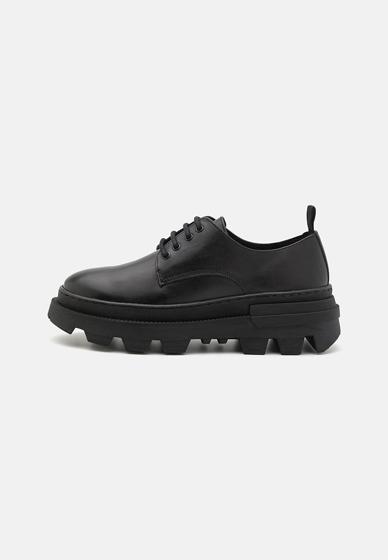 Zwarte leren schoenen met een ronde neus, vetersluiting, dikke rubberen zool en verhoogde accenten aan de zijkant. Voorzien van een trekhaak aan de achterkant.
