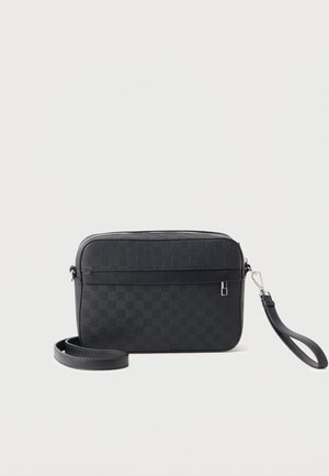 Fekete, texturált keresztpántos táska cipzáras tetejével, levehető csuklópánttal és hosszú, állítható vállpánttal fehér háttéren.