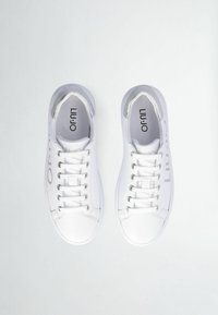 Sneaker bianche realizzate con un materiale similpelle liscio, punte rotonde, dettagli argentati vicino al tallone e sei asole per i lacci.