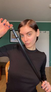 Čierna chodítka s geometrickou kovovou rukoväťou. Hladká textúra s elegantným dizajnom, držená osobou v tmavom tričku s dlhým rukávom.