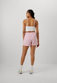 Pantalones cortos a rayas rosa y blancos con cintura elástica, combinados con una camiseta corta blanca, que muestran un diseño casual y ajustado.