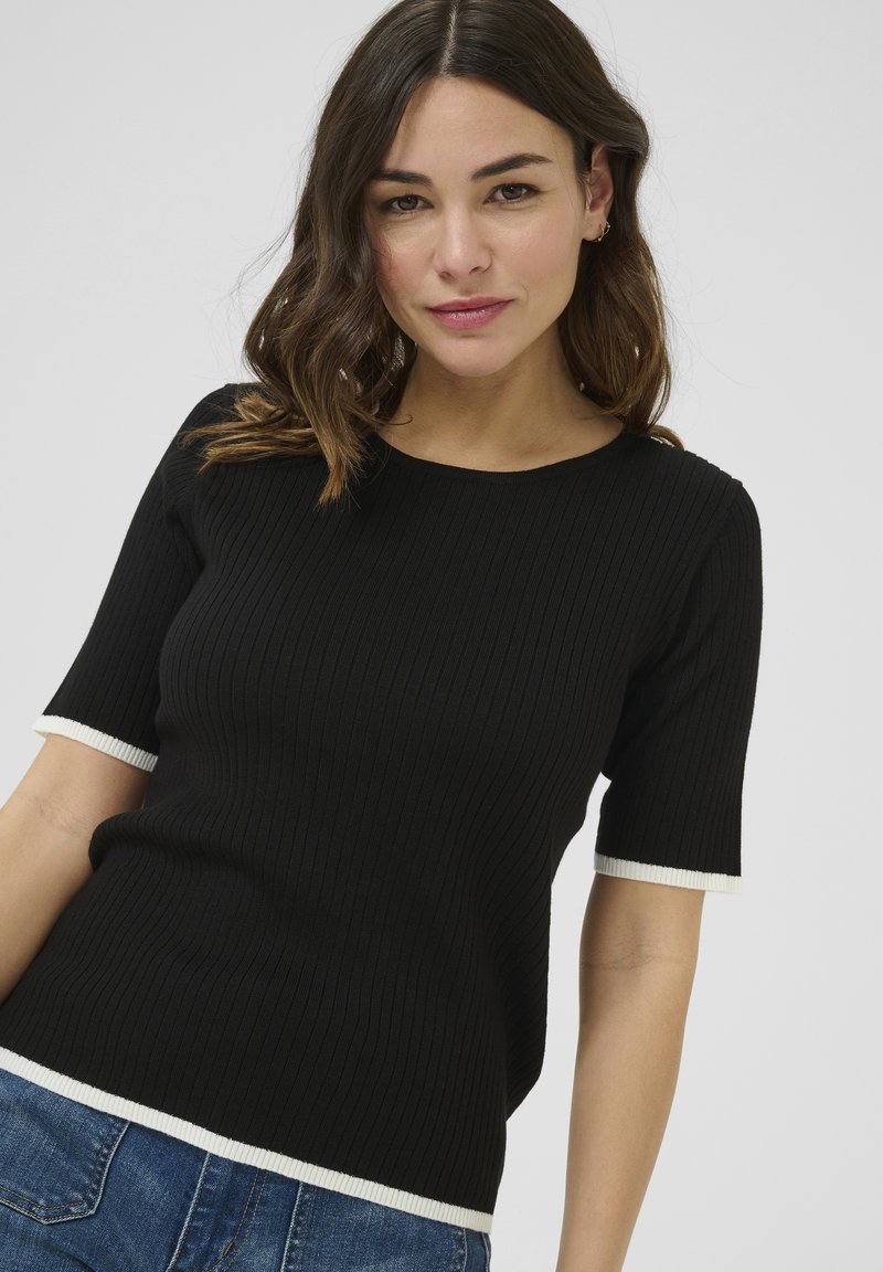 Zwarte geribbelde top met korte mouwen en witte contrasterende boorden en zoom. Zachte textuur, aansluitende vorm en ronde halslijn.