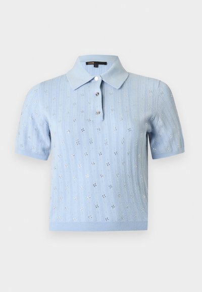 Polo en tricot bleu clair à manches courtes avec motif floral en œillets et trois boutons sur le devant, sur un fond uni.