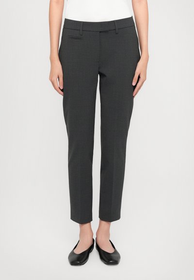 Pantalons tailleur gris avec une coupe slim, présentant une texture lisse, des poches avant et une longueur au-dessus de la cheville. Associés à des ballerines noires.