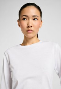 Witte longsleeve t-shirt met een ronde hals, gemaakt van zachte stof, met een gladde textuur en een minimalistisch ontwerp.