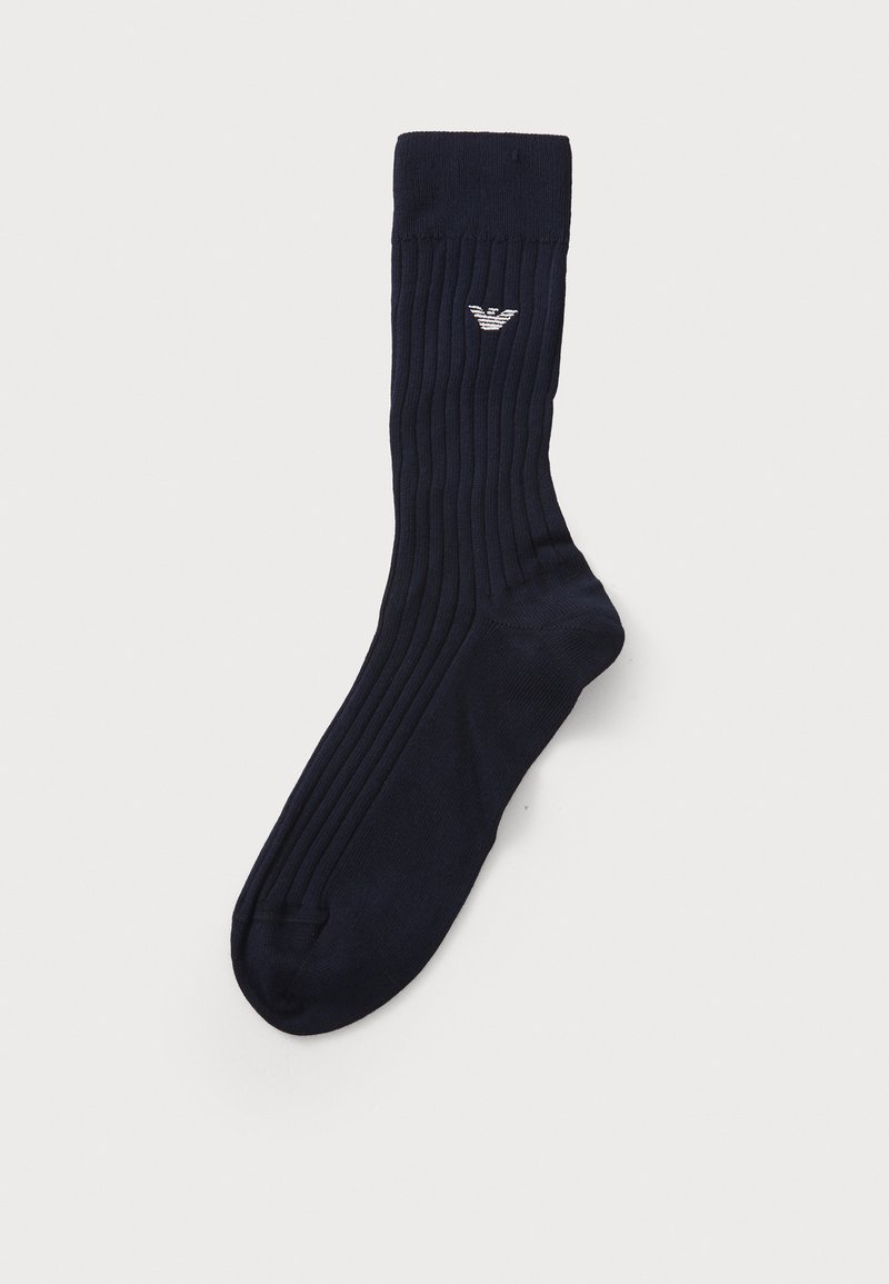 Temno modra rebrasta nogavica iz mehkega materiala, z majhnim belim logotipom na zgornji strani in ojačanim prstom za trpežnost.