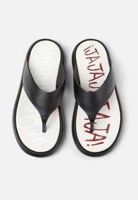 Black flip-flops with a leather strap and white footbed. Text printed in red and white reads "HA HA HA!" and "¡JA JA JA!" in a playful font.