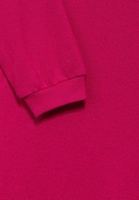 Klart rosa stickad tyg som visar en manschettad långärmad ärm på vänster sida.