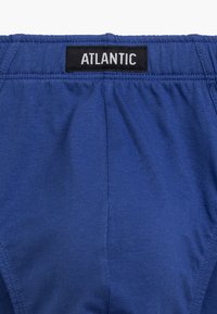 Niebieska bielizna o gładkiej teksturze i elastycznym pasku w talii z czarną metką oznaczoną "ATLANTIC". Prosty, bezszwowy design.