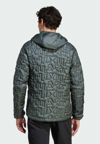 Dunkelgrüne gepolsterte Jacke mit geometrischem Steppmuster und Kapuze. Verfügt über elastische Bündchen und einen leicht verlängerten hinteren Saum.