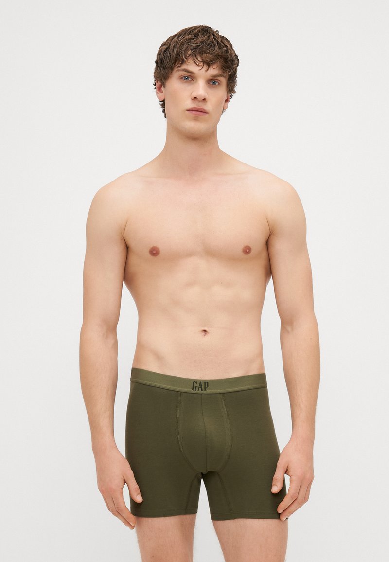 Boxeri din bumbac verde cu o croială ajustată, prevăzuți cu un tiv cu logo. Materialul pare moale și neted, cu un design minimalist, de lungime scurtă.