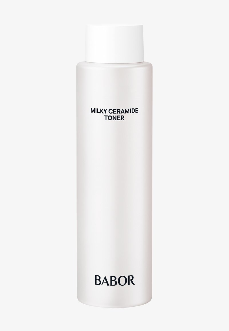 Grande bouteille blanche avec bouchon blanc étiquetée « Milky Ceramide Toner » et nom de la marque « BABOR » en bas sur un fond uni.