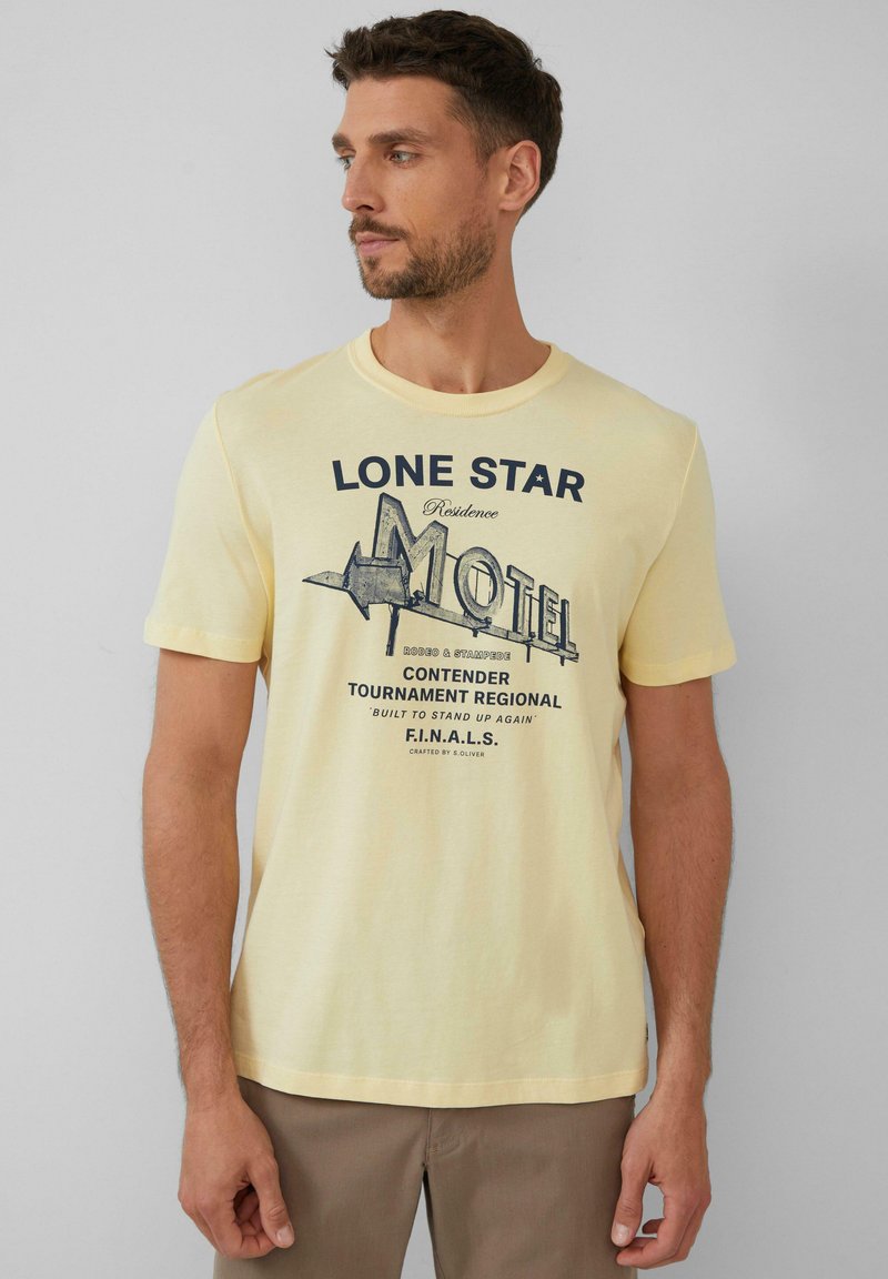 Lichtgele t-shirt met korte mouwen met de opdruk "LONE STAR MOTEL" in donkerblauw, met een ontwerp van een vintage motelbord. Zachte stoffen textuur.