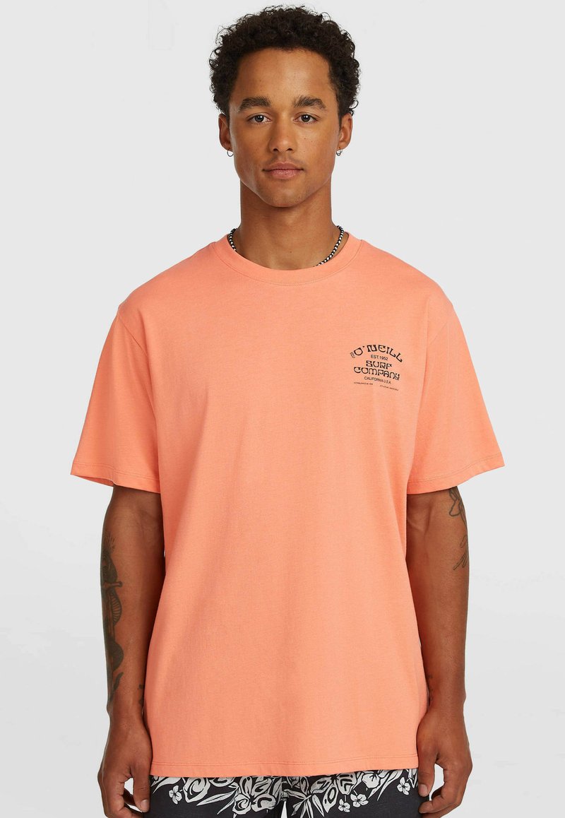 Κοντομάνικο t-shirt σε κοραλλί χρώμα από βαμβάκι, με μικρό μαύρο λογότυπο στην αριστερή πλευρά του στήθους. Ευθεία ραφή στη βάση, χαλαρή εφαρμογή.