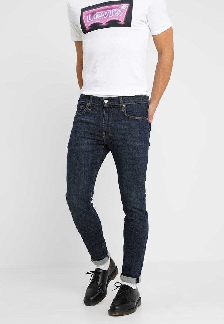 Jeans de mezclilla azul oscuro con un corte ajustado, que cuentan con un diseño clásico de cinco bolsillos y un parche con logo cosido en contraste en la parte trasera.