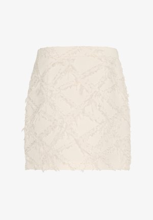 Short white skirt featuring a textured design with frayed accents in a diamond pattern. Made of a lightweight fabric.