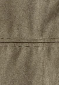 Tissu kaki avec une texture douce et semblable à du daim. Présente une couture visible et un léger éclat, ajoutant de la profondeur à la surface.