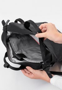 Zaino nero con chiusura a zip, motivo a griglia grigia all'interno, tasche piatte e ferramenta nera. Presenta manici robusti e una tracolla.
