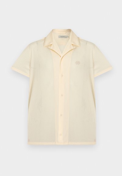 Κοντομάνικο κρεμ πουκάμισο με κουμπιά, μυτερό γιακά και διακριτικό κατακόρυφο διάτρητο σχέδιο, με μικρό κεντημένο λογότυπο στο αριστερό στήθος.