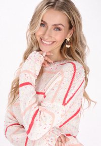 Maglione lavorato a maglia in crema chiaro con strisce diagonali rosa e rosse e macchie colorate. Include maniche lunghe con polsini a coste.