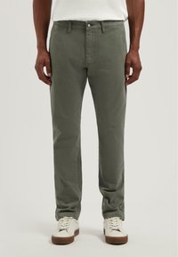 Olívazöld pamut nadrág, slim fit kivitelben, standard derékkal, elülső zsebekkel és kontrasztos fehér varrással.
