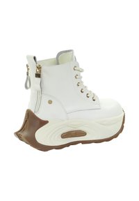 Białe wysokie buty ze sztucznej skóry, posiadające sznurowanie z przodu, zamek błyskawiczny po boku oraz masywną podeszwę w brązowo-kremowym kolorze.