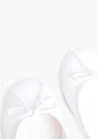 Ballerine bianche in tela, con punta arrotondata, dettagli in tessuto a fiocco e suola liscia. Parte superiore testurizzata con design minimale.