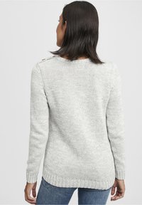 Pull en maille gris clair avec un motif texturé, col arrondi et poignets côtelés. Détail de boutons à l'épaule, coupe longueur hanche.
