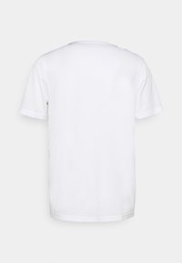 Camiseta blanca de manga corta con cuello redondo y una textura suave. Diseño sencillo y minimalista sin logotipos ni patrones visibles.