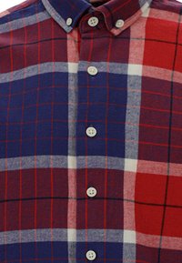 Camicia a quadri rossa, blu e bianca con collo a camicia, diversi bottoni e tessuto morbido.