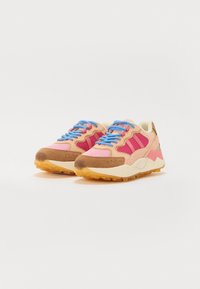 Sportssko med en blanding af pink og tan materialer, med blå snørebånd og teksturerede såler. Inkluderer tre striber detaljer på siden.