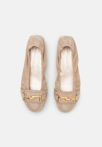 Beige semskede leiligheter med rund tå og en dekorativ gullspenne på stroppen. Myk tekstur og et interiør med en skinnende finish.