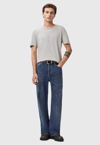 T-shirt a girocollo grigio chiaro abbinata a jeans a gamba larga blu. I jeans presentano un classico design a cinque tasche e una sottile texture scucita.