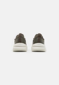 Brown athletic shoes with a sleek design, featuring a textured mesh upper, pull tab, and white cushioning sole.